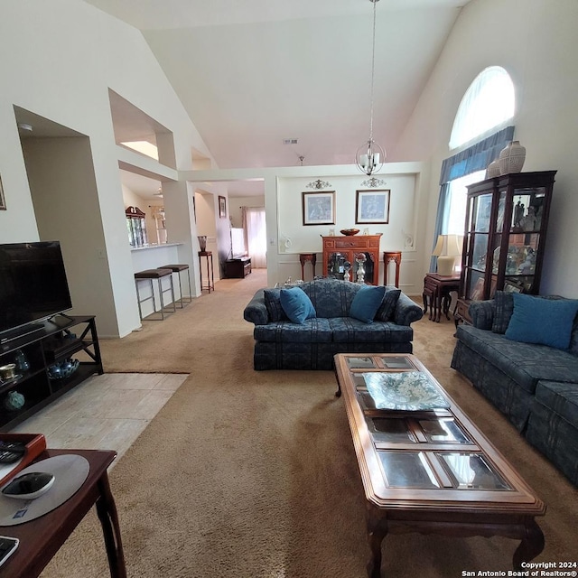 carpeted living room featuring high vaulted ceiling and an inviting chandelier