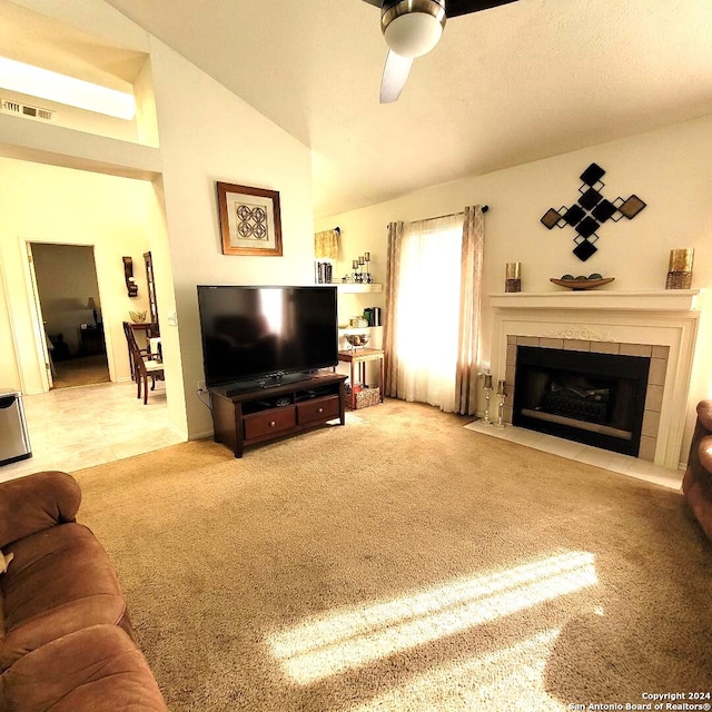 living room with carpet, ceiling fan, lofted ceiling, and a tile fireplace