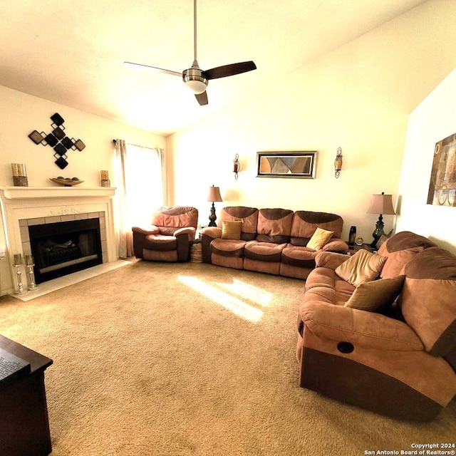 carpeted living room featuring a tile fireplace, vaulted ceiling, and ceiling fan