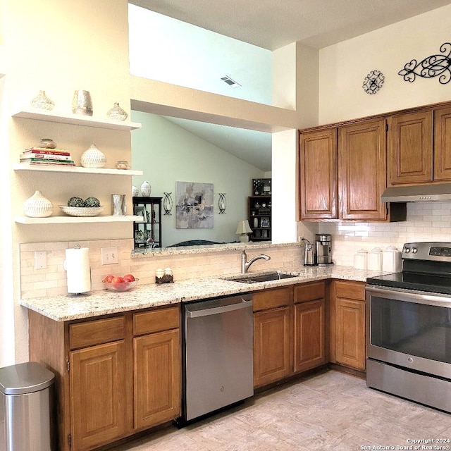 kitchen featuring backsplash, sink, vaulted ceiling, appliances with stainless steel finishes, and light stone counters