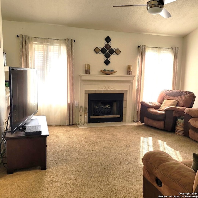 carpeted living room with a tile fireplace, a wealth of natural light, a textured ceiling, and ceiling fan