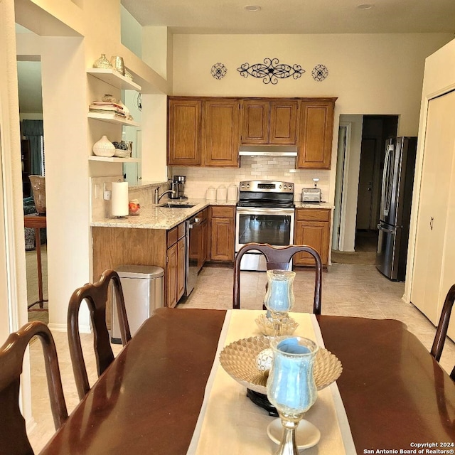 kitchen with sink, decorative backsplash, light tile patterned flooring, light stone counters, and stainless steel appliances