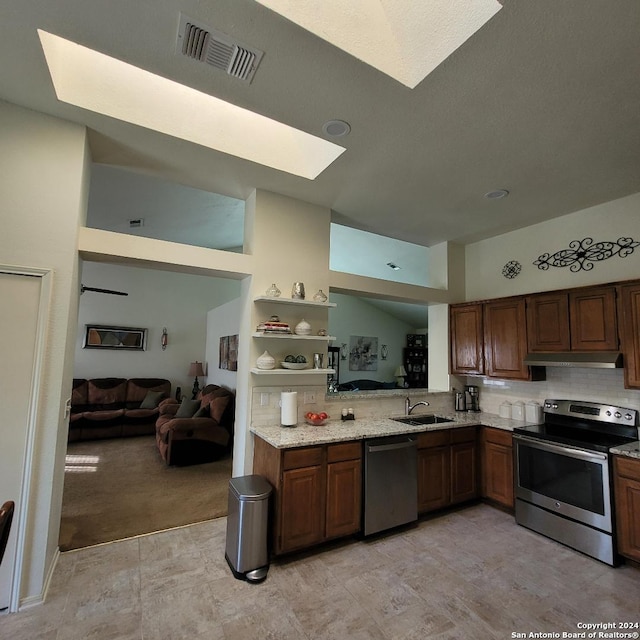 kitchen with sink, light stone counters, light colored carpet, extractor fan, and appliances with stainless steel finishes