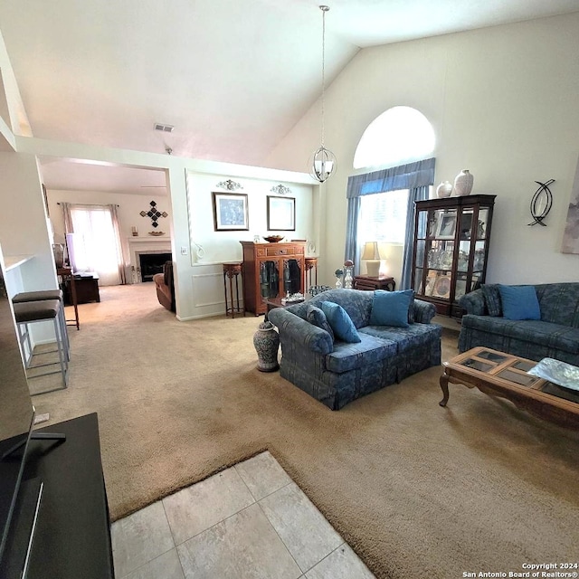 carpeted living room featuring an inviting chandelier and high vaulted ceiling