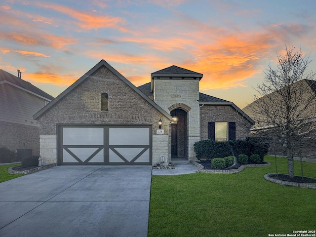 french country style house with a lawn, a garage, and central AC