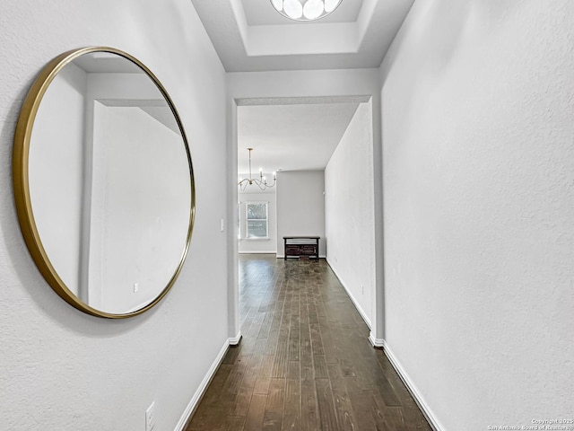 hallway with dark hardwood / wood-style flooring and an inviting chandelier