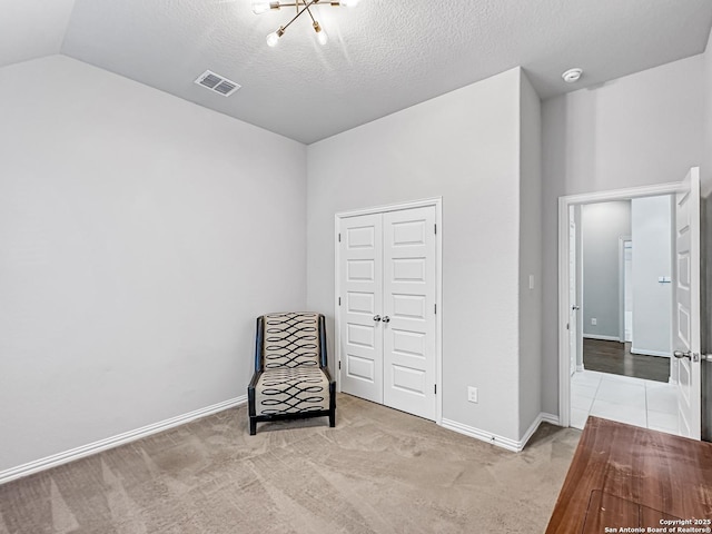 unfurnished room featuring light colored carpet, lofted ceiling, a textured ceiling, and an inviting chandelier