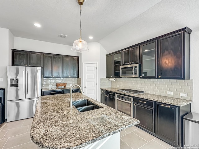 kitchen featuring a kitchen island with sink, sink, decorative backsplash, decorative light fixtures, and stainless steel appliances