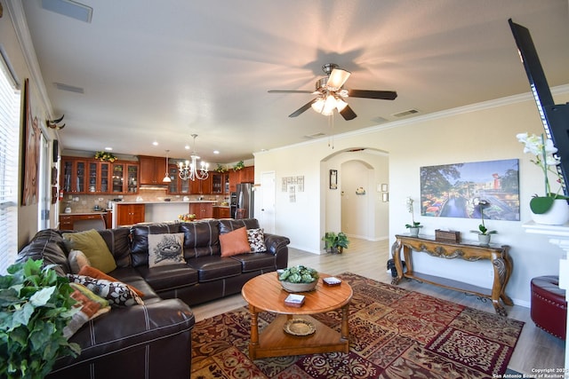 living room featuring crown molding, ceiling fan with notable chandelier, and light wood-type flooring