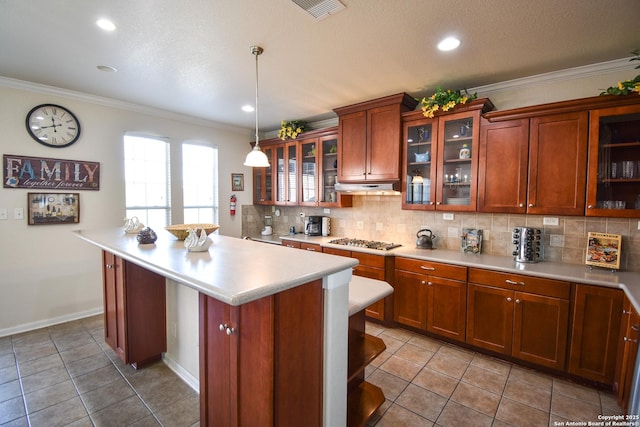 kitchen with pendant lighting, stainless steel gas stovetop, a breakfast bar, crown molding, and light tile patterned floors