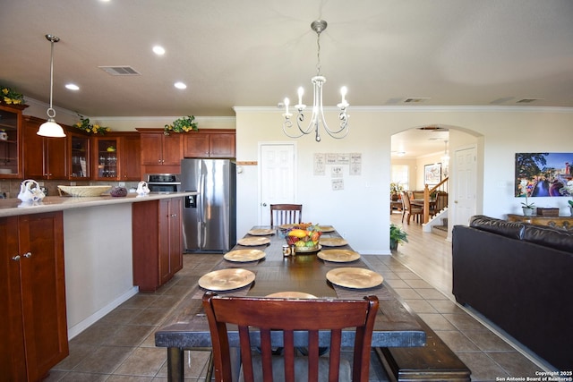 tiled dining space with crown molding and a notable chandelier