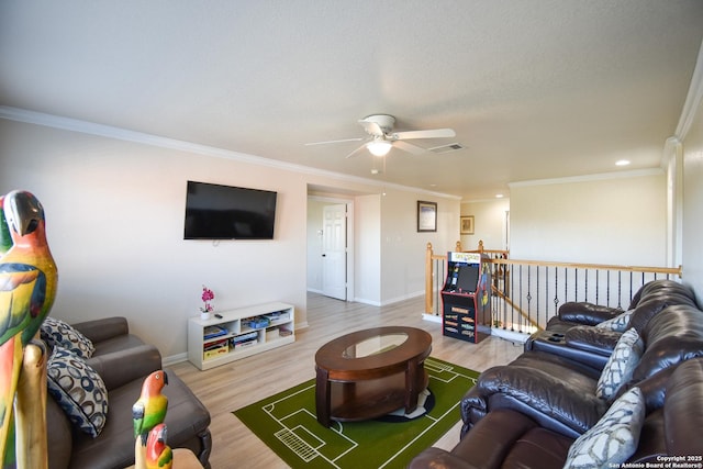 living room with hardwood / wood-style flooring, ceiling fan, and crown molding