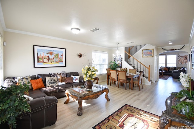 living room with light wood-type flooring, crown molding, and a notable chandelier