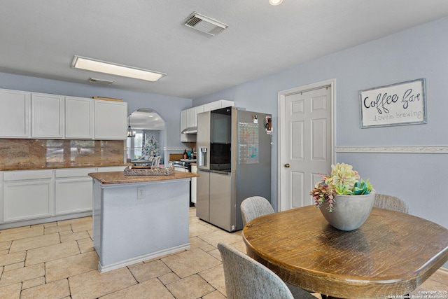 kitchen featuring white cabinets, decorative backsplash, stainless steel fridge, and a center island