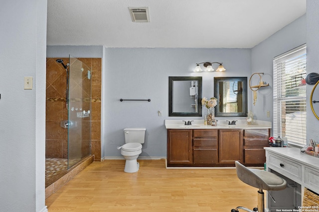 bathroom featuring tiled shower, vanity, hardwood / wood-style flooring, and toilet