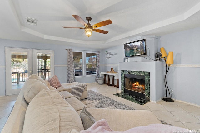 living room featuring french doors, a tray ceiling, ceiling fan, and light tile patterned flooring