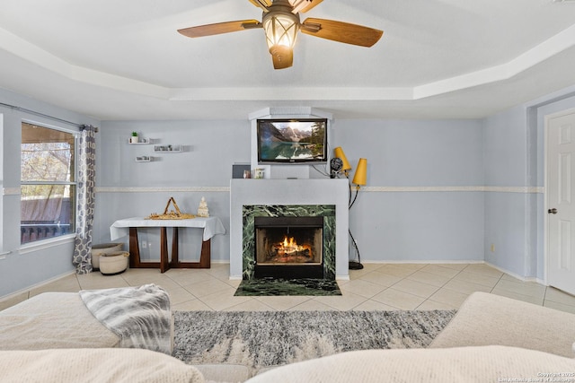 living room featuring tile patterned flooring, a raised ceiling, and a premium fireplace