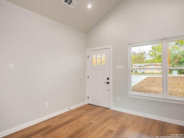 foyer entrance with light hardwood / wood-style floors, high vaulted ceiling, and plenty of natural light