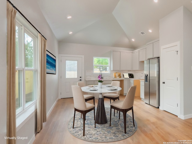 dining space with a wealth of natural light, light hardwood / wood-style floors, and vaulted ceiling