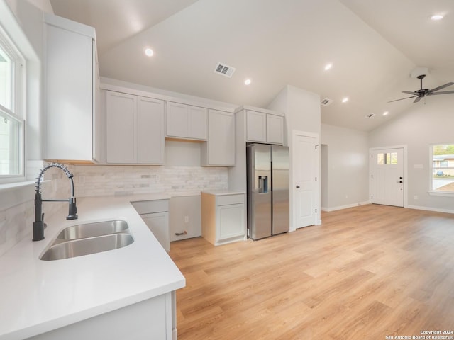 kitchen with ceiling fan, sink, backsplash, stainless steel fridge, and lofted ceiling