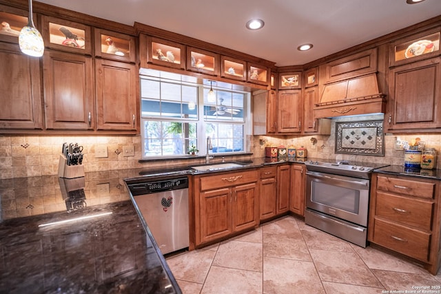 kitchen with sink, stainless steel appliances, tasteful backsplash, pendant lighting, and custom range hood