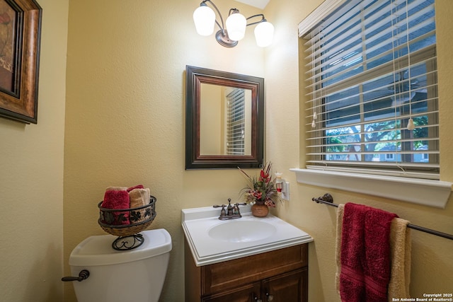 bathroom with a notable chandelier, vanity, and toilet