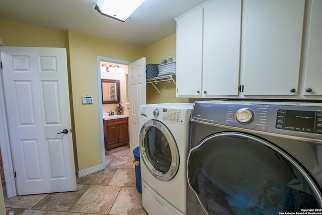 laundry room featuring cabinets, sink, light tile patterned flooring, and washing machine and clothes dryer