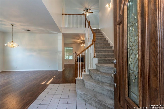 foyer entrance featuring tile patterned floors and ceiling fan with notable chandelier