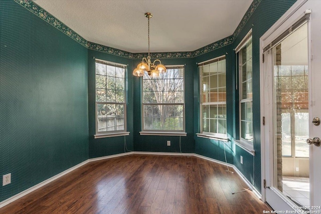 unfurnished dining area with hardwood / wood-style floors and an inviting chandelier