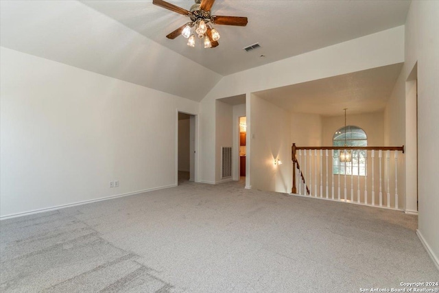 carpeted spare room with ceiling fan with notable chandelier and vaulted ceiling