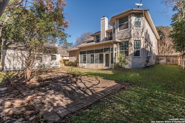 back of house featuring a sunroom, a patio area, and a yard