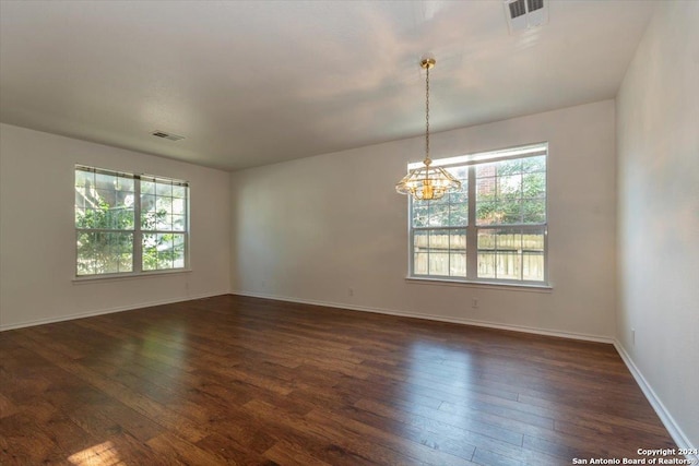 empty room featuring a notable chandelier and dark hardwood / wood-style flooring