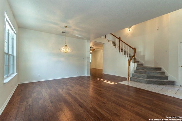 spare room with hardwood / wood-style floors, a textured ceiling, and an inviting chandelier