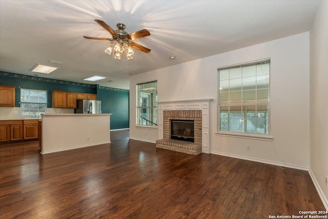 unfurnished living room featuring dark hardwood / wood-style floors, a brick fireplace, ceiling fan, and sink