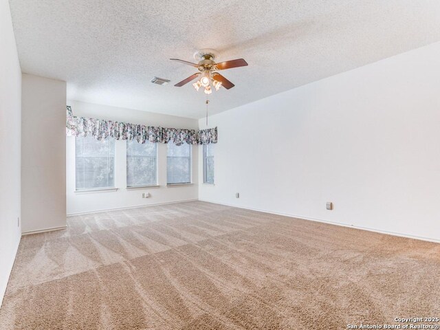 carpeted empty room featuring ceiling fan and a textured ceiling