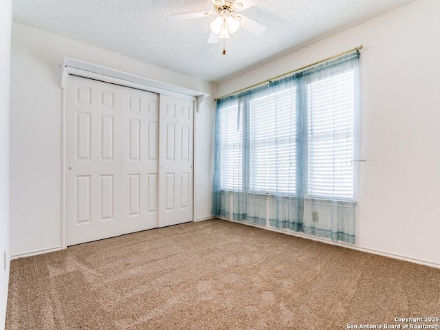 unfurnished bedroom featuring ceiling fan, carpet flooring, a closet, and a textured ceiling