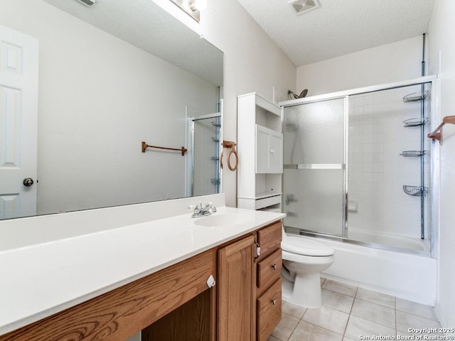 full bathroom with tile patterned flooring, bath / shower combo with glass door, vanity, a textured ceiling, and toilet