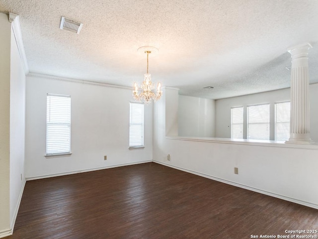 unfurnished room with decorative columns, dark hardwood / wood-style floors, a notable chandelier, and a textured ceiling