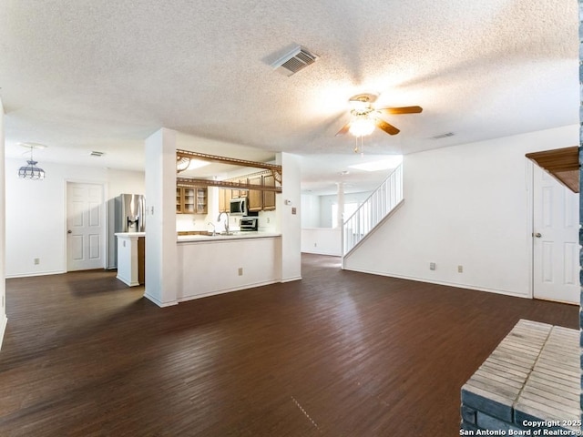 unfurnished living room with sink, a textured ceiling, dark wood-type flooring, and ceiling fan