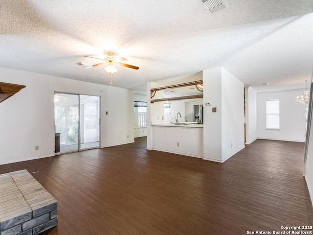 unfurnished living room with sink, ceiling fan with notable chandelier, a textured ceiling, and dark hardwood / wood-style flooring