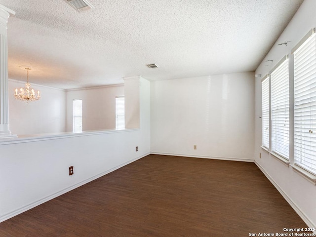 spare room with dark wood-type flooring, an inviting chandelier, and a textured ceiling