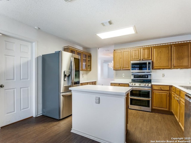 kitchen with stainless steel appliances, dark hardwood / wood-style flooring, a kitchen island, and a textured ceiling