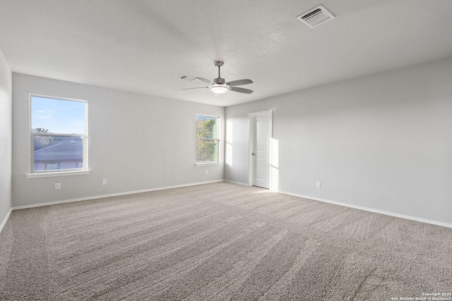 carpeted empty room featuring ceiling fan and a textured ceiling