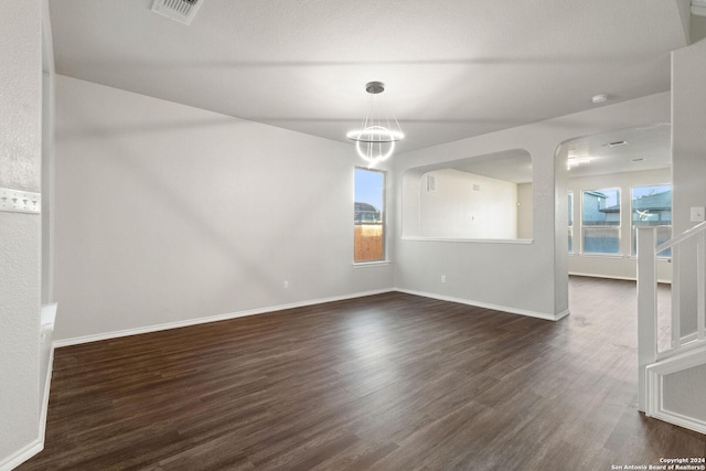 empty room featuring dark hardwood / wood-style flooring and a notable chandelier