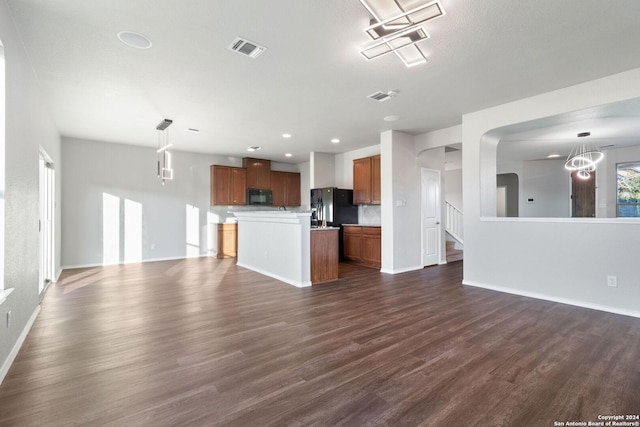 unfurnished living room with a chandelier and dark hardwood / wood-style floors