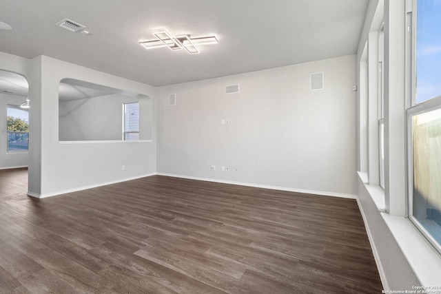 unfurnished room featuring dark wood-type flooring and a textured ceiling