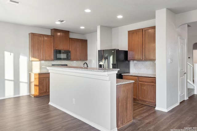 kitchen with sink, dark hardwood / wood-style flooring, backsplash, an island with sink, and black appliances