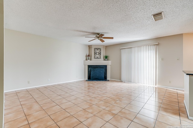 unfurnished living room featuring ceiling fan, light tile patterned floors, and a textured ceiling