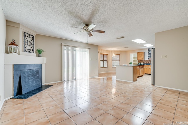 unfurnished living room with ceiling fan, light tile patterned floors, and a textured ceiling