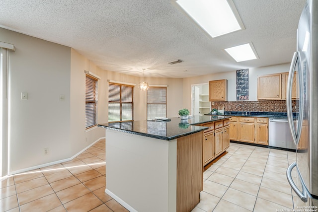 kitchen featuring hanging light fixtures, stainless steel appliances, a kitchen island, a chandelier, and light tile patterned flooring